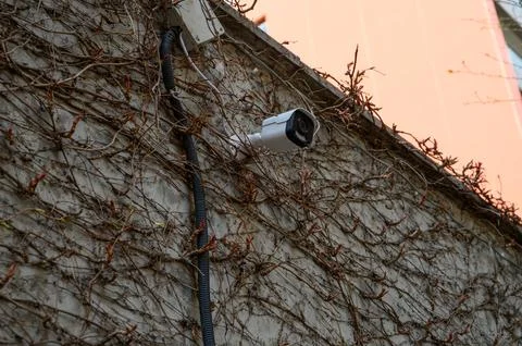 IP security camera mounted on building wall with Power over Ethernet PoE co.. Stock Photos