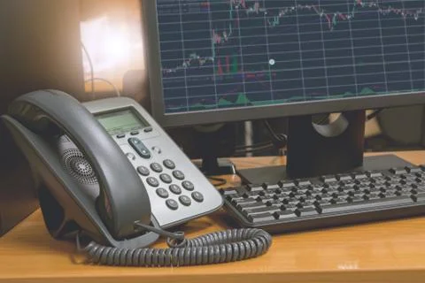 IP telephone with computer keyboard and monitor display financial chart on sc Foto stock