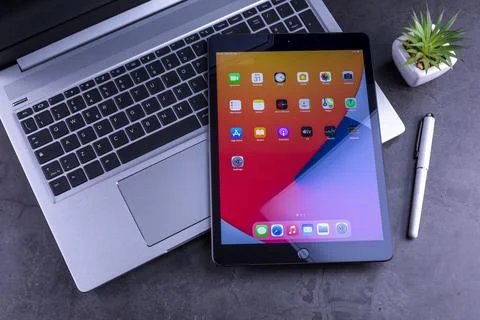 IPad 8th generation over silver laptop on desktop Фото