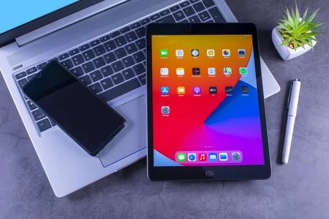 IPad 8th generation over silver laptop on desk Stock Photos