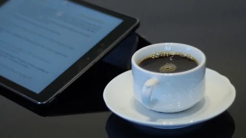 Ipad with full white cup of coffee on a saucer Stock Footage 74570493