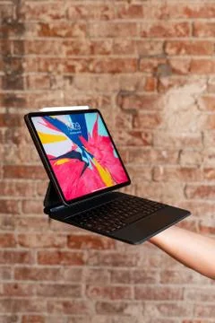 IPad on Magic Keyboard held by a hand Foto stock