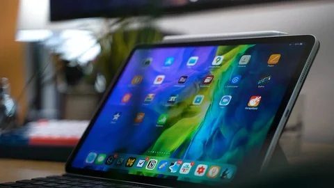 IPad Pro on desk on home screen, slider shot, medium view, plant in foreground Stock-Footage 129153355