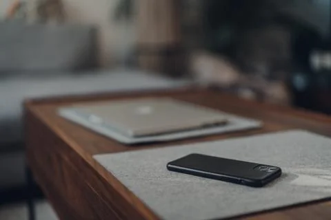 IPhone 11 Pro Max by Apple on a table at home, closed laptop on background, s Stock Photos