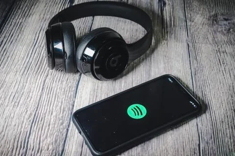 An iphone 11 screen showing spotify icon with beats earphone Stock Photos