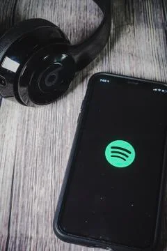 An iphone 11 screen showing spotify icon with beats earphone Stock Photos