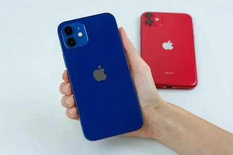 IPhone 12 in blue next to iPhone 11 in red. Stock Photos