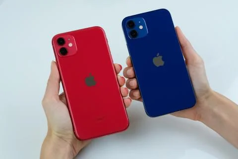 IPhone 12 in blue next to iPhone 11 in red. Stock Photos