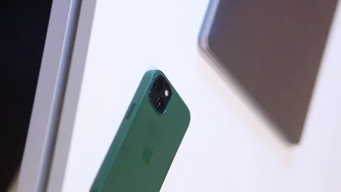IPhone 15 in a green case, lying on a table, close-up, blurred background. Stock Footage 282976019