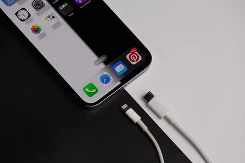 An iPhone 15 with the open menu that has the new type c charger next to it Stock Photos