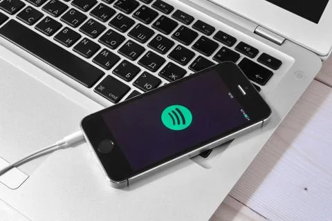 IPhone 5s on laptop with mobile application for Spotify on the screen Stock Photos