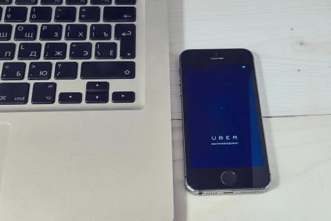 IPhone 5s on laptop with mobile application for Uber on the screen Fotos Stock