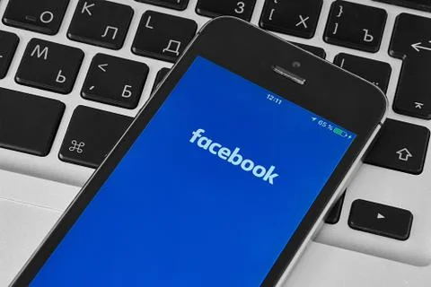 IPhone 5s on laptop with mobile application for Facebook on the screen Stock Photos
