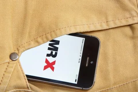 IPhone 5s with mobile application for MR X on the screen in orange jeans pock 写真素材