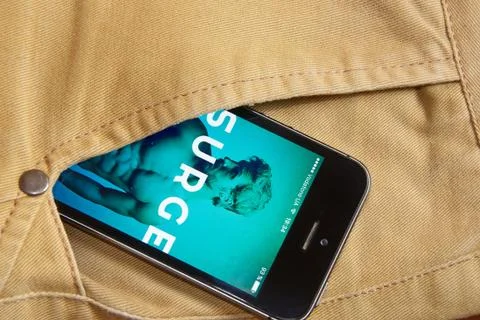 IPhone 5s with mobile application for Surge on the screen in orange jeans pocket Stock Photos