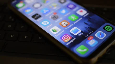 Iphone by apple on the laptop keyboard. iphone screen in a camera motion. Stock Footage 229770064