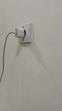 The iPhone power adapter is installed in the power plug. Stock Photos