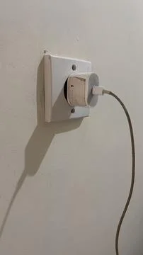 The iPhone power adapter is installed in the power plug. Stock Photos