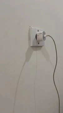IPhone power adapter is installed in the power plug. Stock Photos