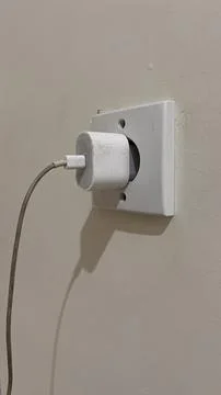 IPhone power adapter is installed in the power plug. Stock Photos