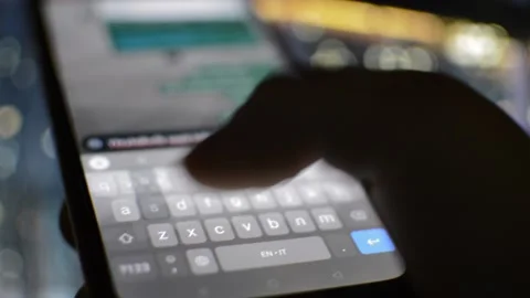 Iphone type city blur background. man type on the iphone in night city. 库存影片 235984774