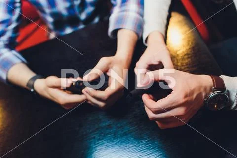 IQOS heat-not-burn tobacco product technology. Two Man holding e-cigarette in Stock Photos