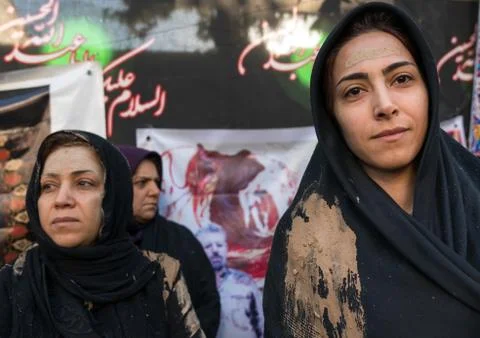 Iranian shiite muslim women with mud stains watch the rubbing mud ritual during Stock Photos