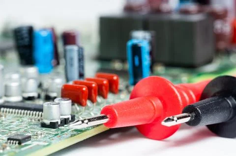?ircuit board with electronic components and a multimeter with test probes. Stock Photos