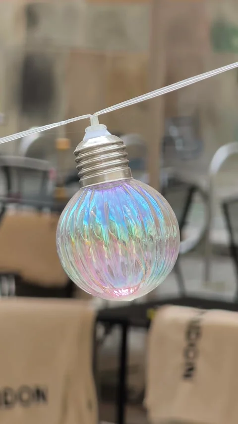 Iridescent Bulb String Light Swaying In Wind At Cozy Outdoor Cafe Close Up Stock Footage 340255818