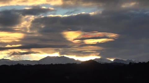 Iridescent clouds glow with rainbow colors above snow capped peaks before Stock Footage 339339487