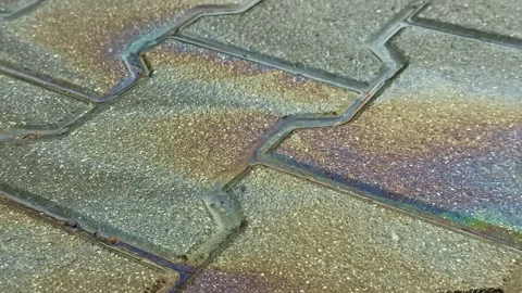 Iridescent rainbow-like pattern on a wet textured pavement surface oil gasoline Video stock 325057335