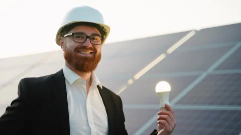 Irish engineer holding light bulb in solar panel farm Stock Footage 314409971