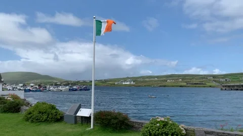 Irish flag on a big white pole is waiving from a heavy wind. Portmagee, Ireland Stock Footage 247549585