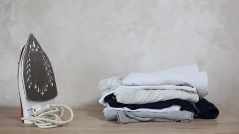 An iron and clean clothes are on the table Stock Footage 271578038