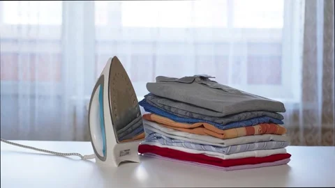 Iron and a stack of clean clothes on an ironing board. Stop motion animation Stock Footage 158874343