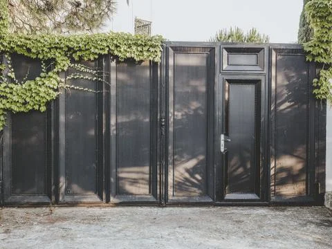 Iron black fence with a gate with a rectangular pattern and ivy on them Stock Photos