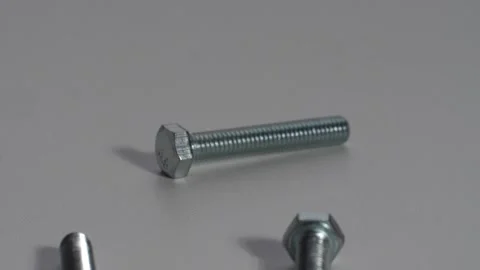 Iron bolts fall on a white table and crumble bouncing in slow motion Stock Footage 131563717