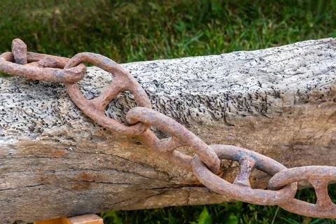 Iron chain corroded by rust on the background of a wooden beam close-up Stock Photos