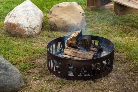 Iron fire ring in a public park with charred logs inside Stock Photos