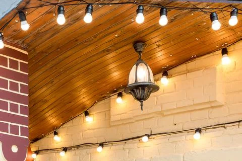 Iron hanging on the ceiling retro lantern with a light bulb on the facade. Stock Photos