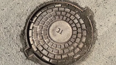 A iron hatch with a pattern above an observation well is located on auto road in Vídeo Stock 274418626