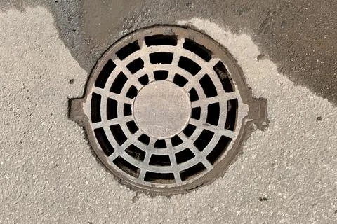 A iron hatch with a pattern above an observation well is located on auto road in Stock Photos