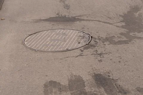 A iron hatch with a pattern above an observation well is located on auto road in Stock Photos