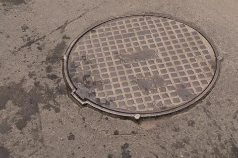 A iron hatch with a pattern above an observation well is located on auto road in Stock Photos