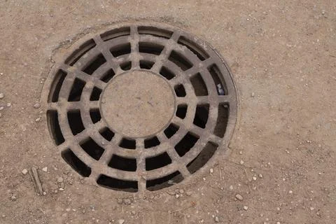 A iron hatch with a pattern above an observation well is located on auto road in Stock Photos