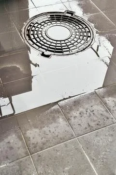 A iron hatch with a pattern and covered water above an observation well is Stock Photos