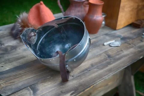 Iron helmet with visor upside down with leather straps lies on a wooden table Stock Photos