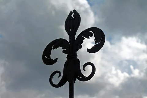 The iron lily on the top of a tower with a dramatic clouded sky Stock Photos