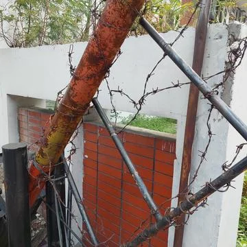 Iron pole entry gate with barbed wire installed Stock Photos