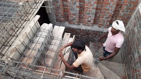 Iron rod frame work being laid down on wooden shuttering for casting RCC stairs Stock Footage 201622020